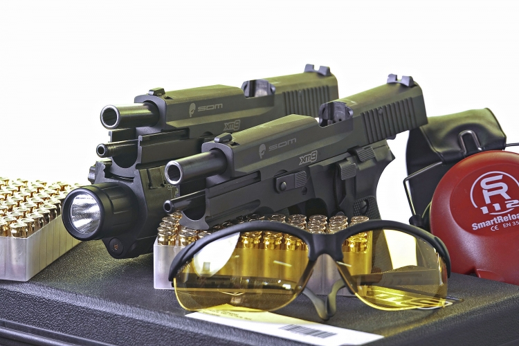 Left to right: the S.D.M. XM9 Operator variant, factory-issued with a tactical flashlight, and the baseline S.D.M. XM9 Tactical model